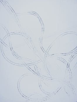 Artistic abstract pattern created by car tracks in the snow, showing intricate loops and curves.