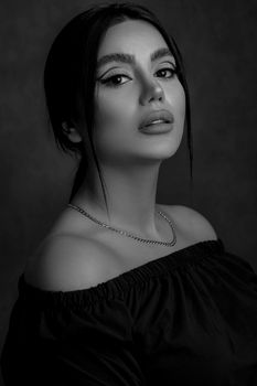 A striking black and white portrait of a woman with elegant features and stylish off-shoulder attire.