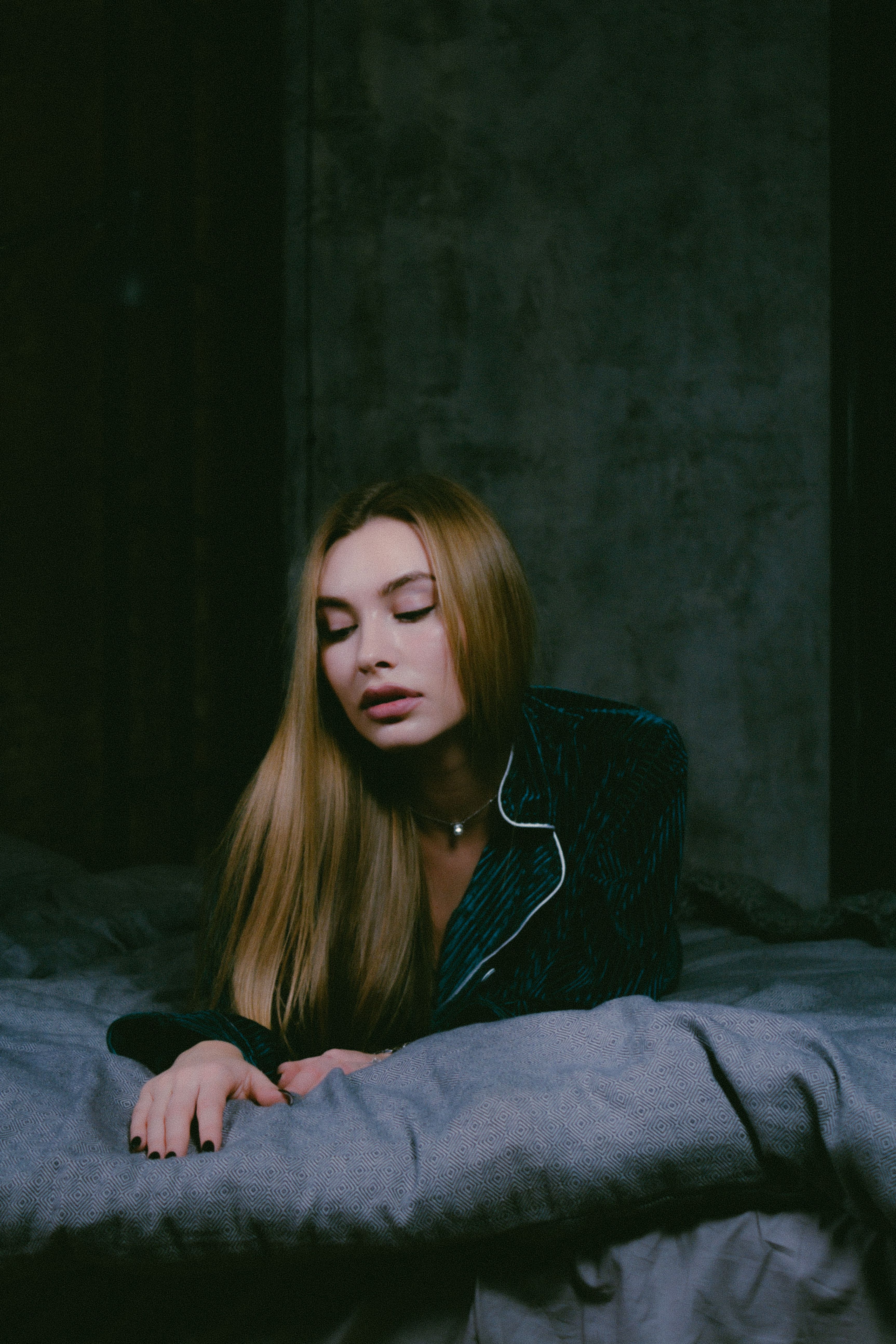 Serene woman in green pajamas resting on bed, exuding calmness and serenity.
