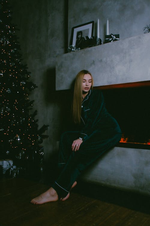 A Woman Sitting on a Faux Fireplace