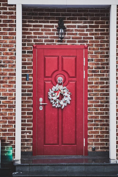 Red Wooden Door with Christmas Wreath on Brown Brick Wall