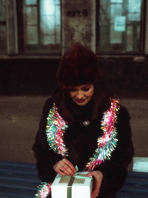 Woman Wearing a Tinsel Around Her Neck and Opening a Present 