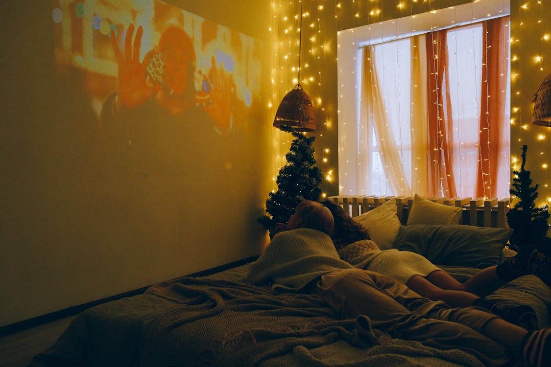 Children Lying Down on Bed and Watching Movie on Wall