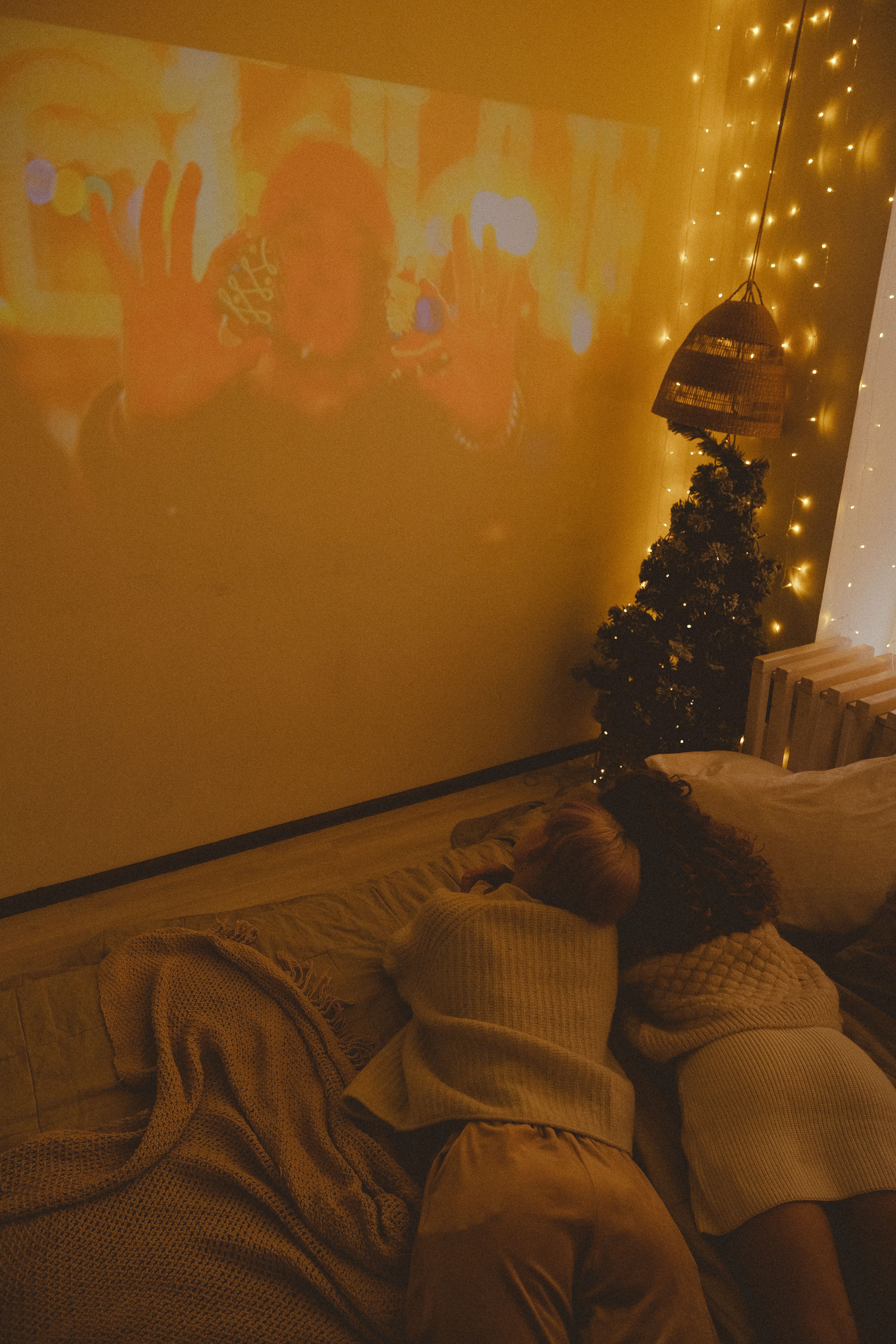 A warm and cozy Christmas scene featuring friends enjoying a movie with holiday decorations.