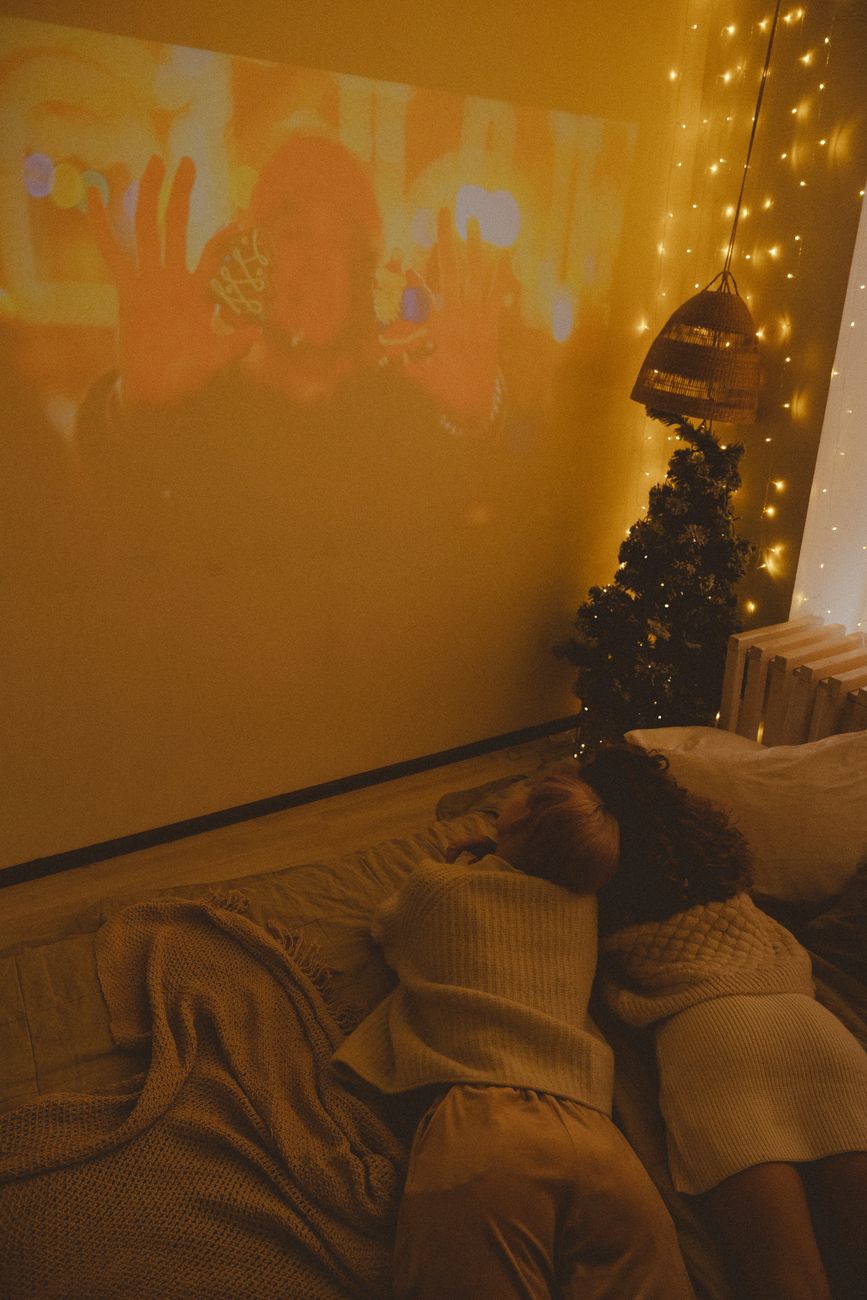 A warm and cozy Christmas scene featuring friends enjoying a movie with holiday decorations.