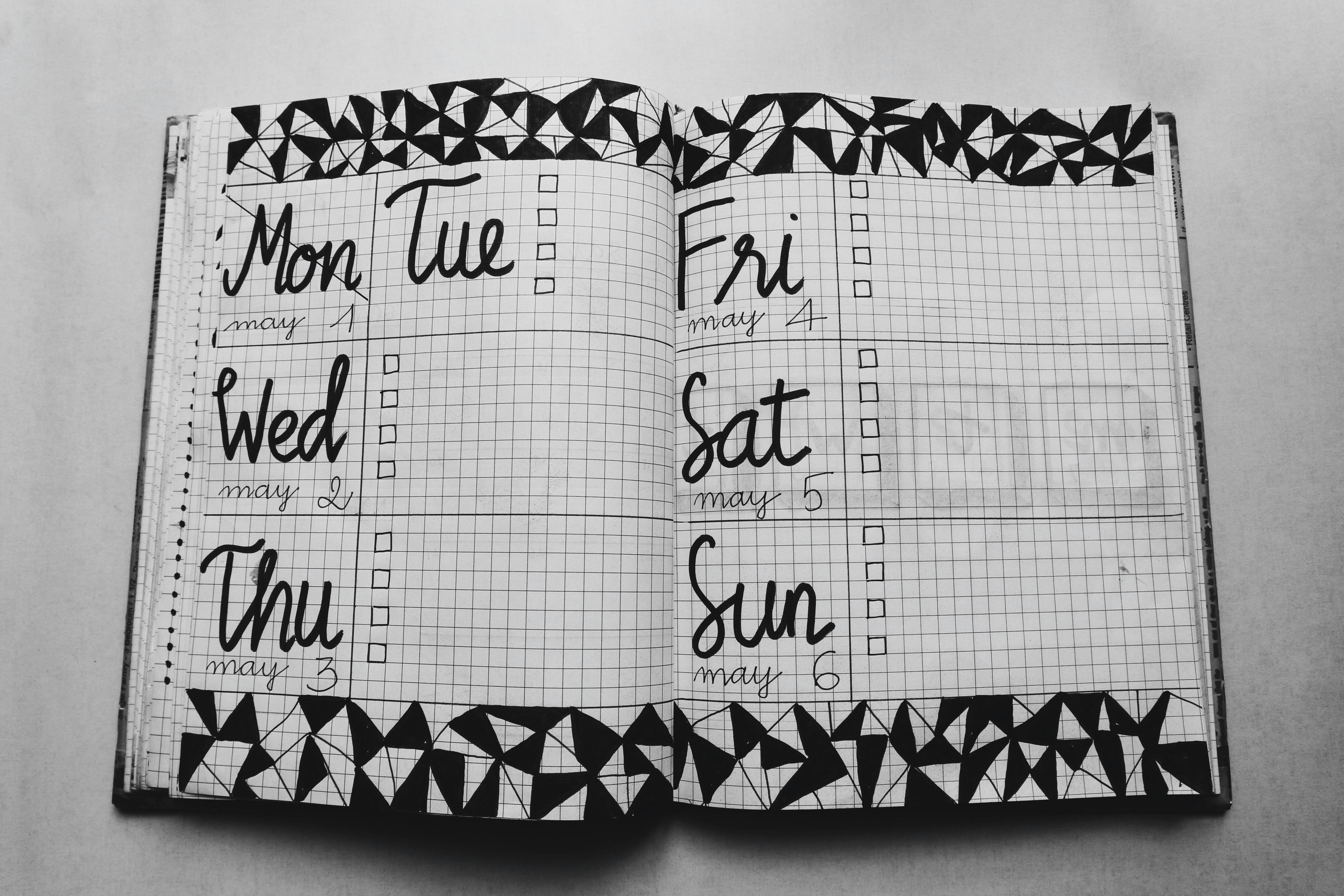 White and Black Weekly Planner on Gray Surface