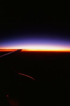 Silhouette of an airplane wing against a stunning sunset sky with vivid colors.