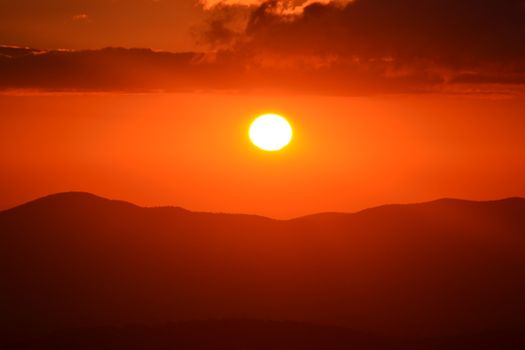 Captivating view of a vibrant sunset casting orange hues over silhouetted mountains.