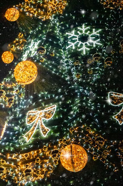 Festive Christmas tree decorated with lights and ornaments in a snowy night scene.