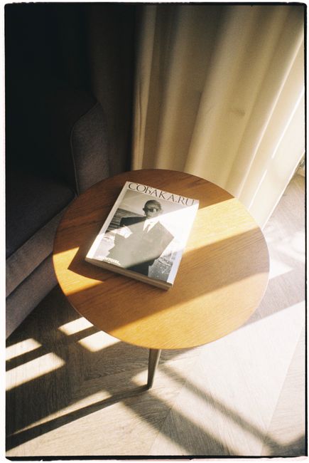 Magazine on a wooden table with sunlight streaming through a curtain, creating a warm ambiance.