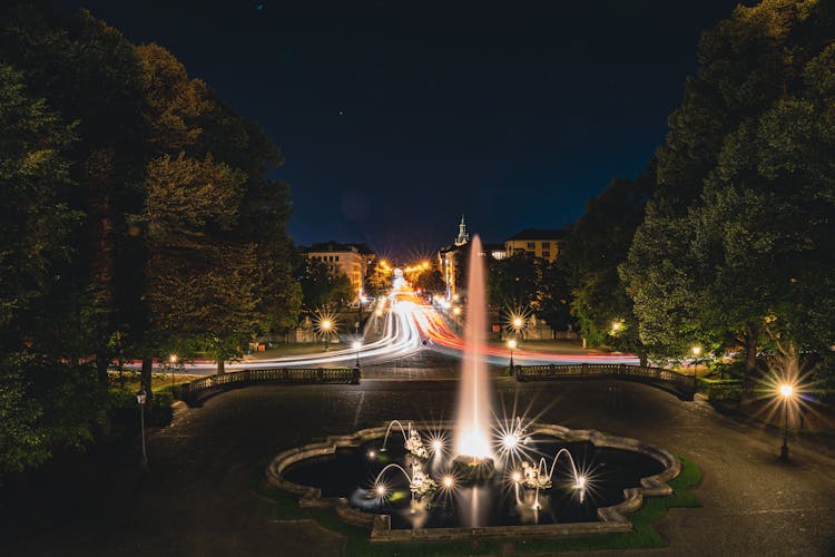 Illuminated Fountain In City At Night