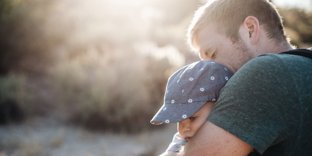 A father hugging his baby outdoors on a sunny afternoon