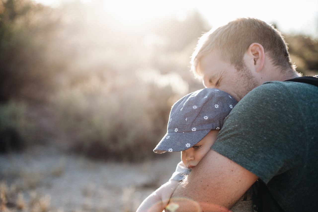 a father lovingly embraces his baby outdoors on a sunny day perfect fo