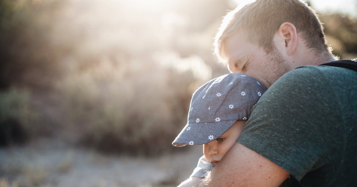 Man Hugging the Baby in Blue Floral Fitted Cap during Daytime