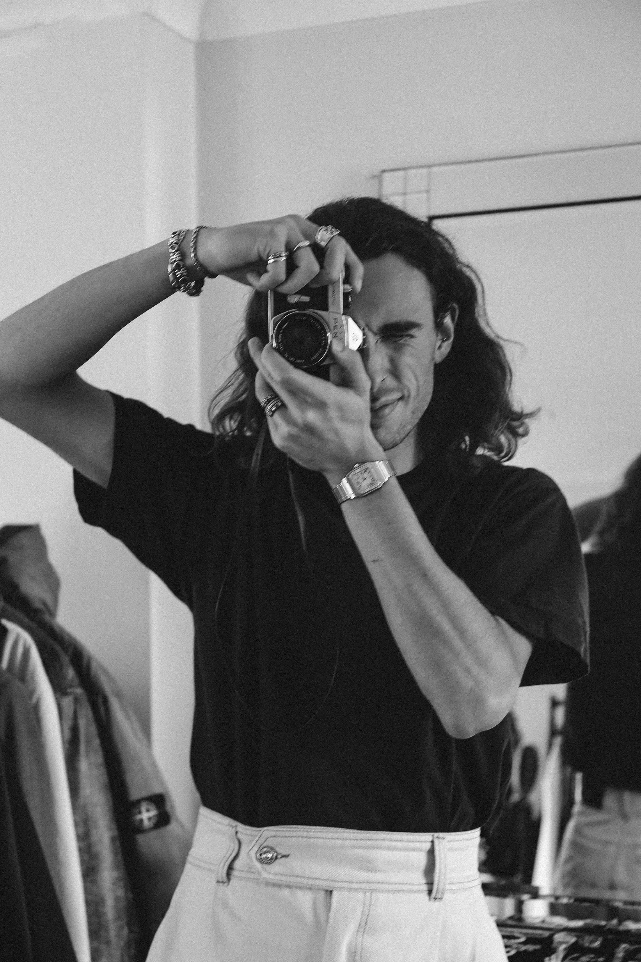 Black and white photo of a man capturing a moment with a classic camera.