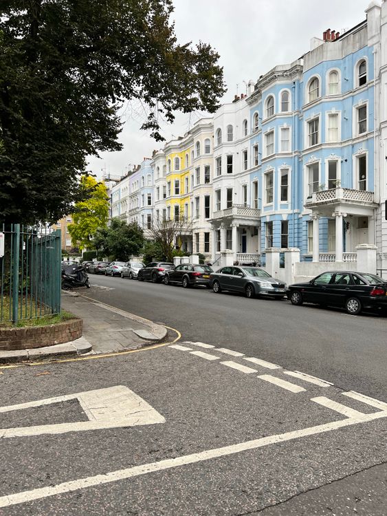 Free A row of Victorian townhouses with pastel facades line a quiet urban street. Stock Photo