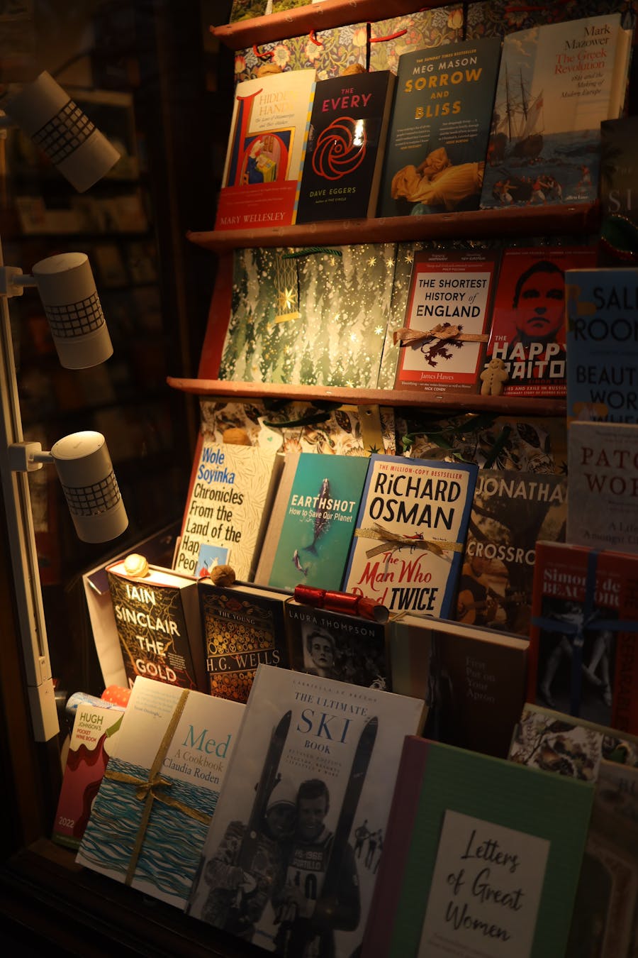 Warmly lit bookstore window display featuring a variety of books and novels at night.