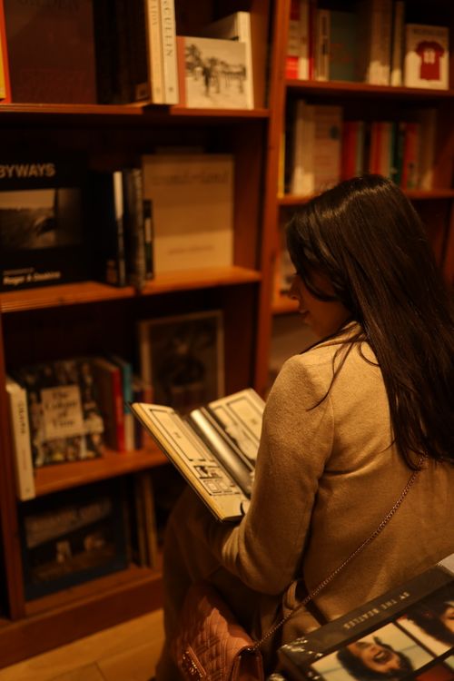 Free A woman reading a book in a warm and cozy library setting. Stock Photo