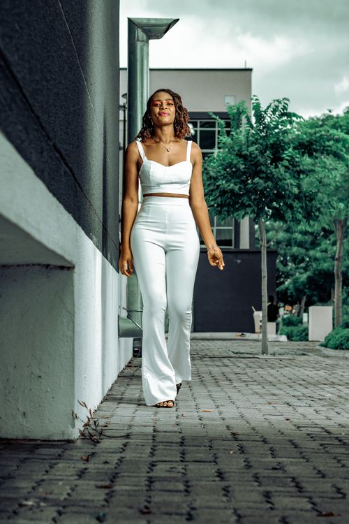 Free Young African American woman confidently walking outside in white clothing. Stock Photo
