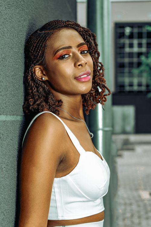 Free Portrait of a fashionable woman leaning against a wall, exuding confidence and style. Stock Photo