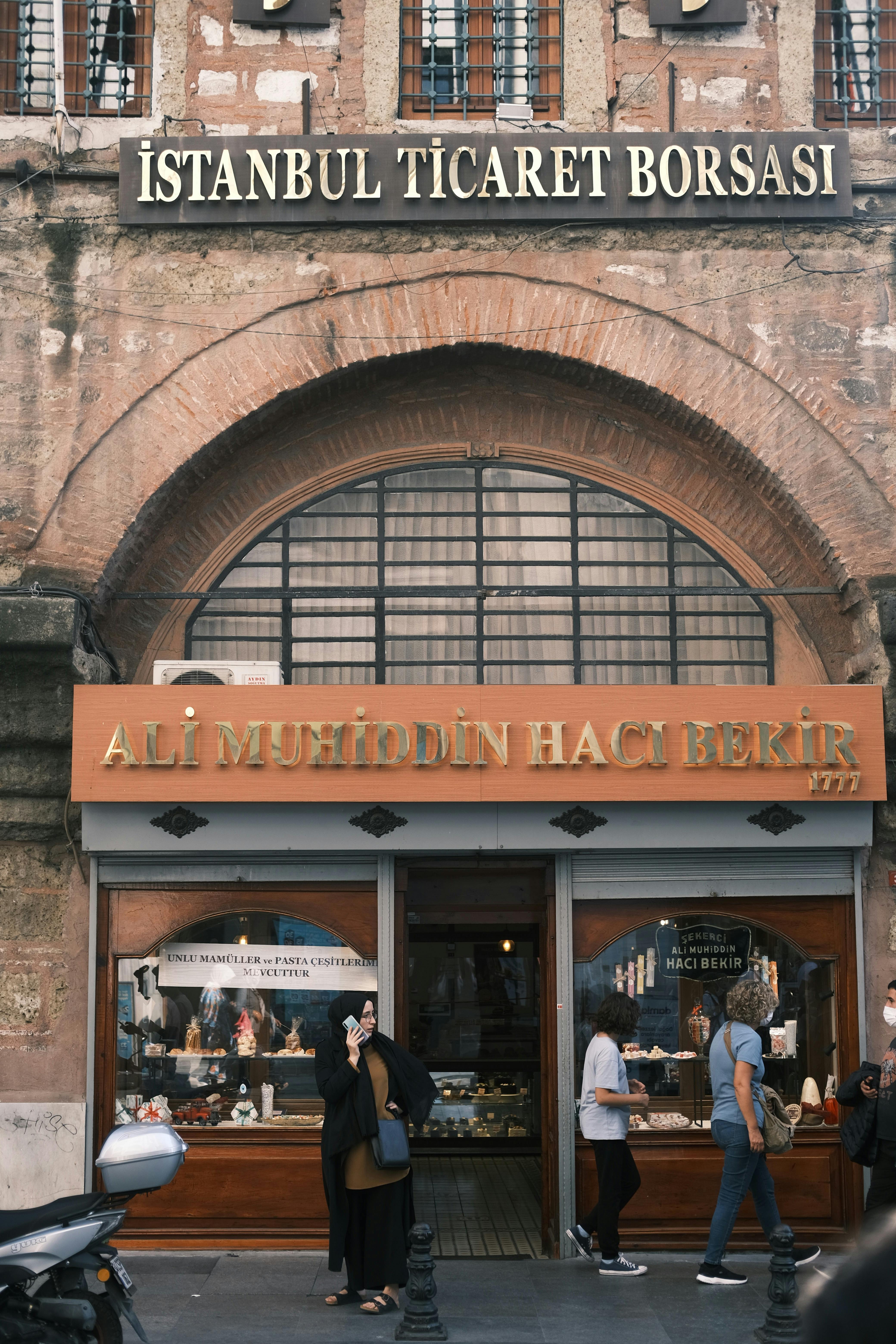 Pedestrians walking by Istanbul's historic Ali Muhiddin Hacı Bekir, famous for Turkish delight.