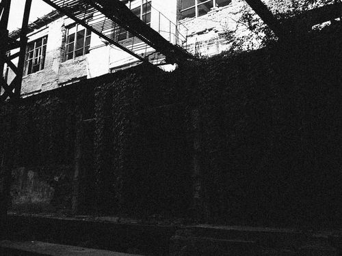 Free Eerie black and white photo of a deteriorating industrial building. Stock Photo