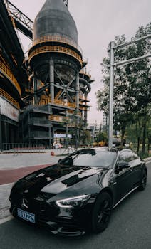 Black luxury car parked near industrial architecture in Beijing, China.