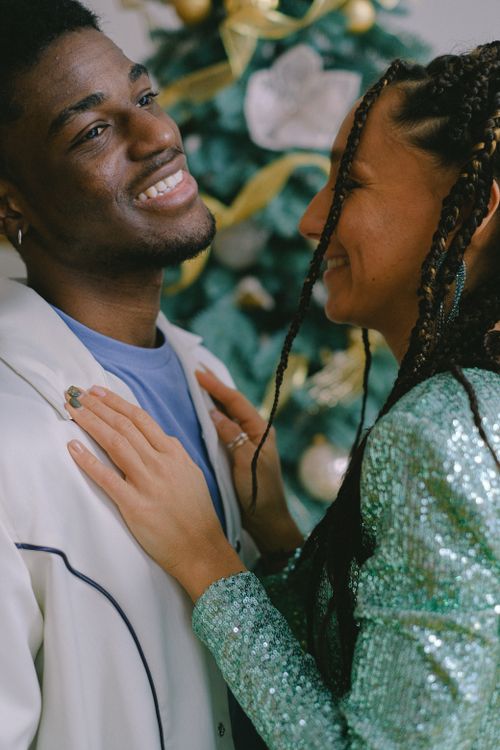 Free Smiling couple sharing a tender moment near a decorated Christmas tree indoors. Stock Photo