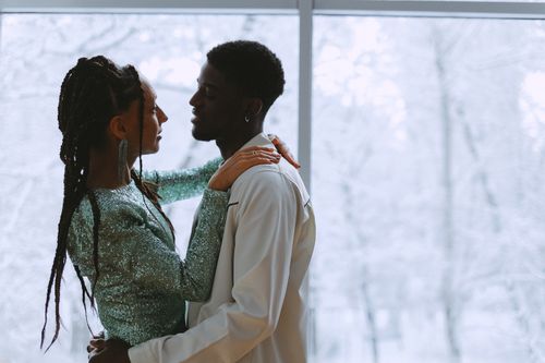 Free Close-up of an African American couple embracing warmly inside with a winter backdrop. Stock Photo