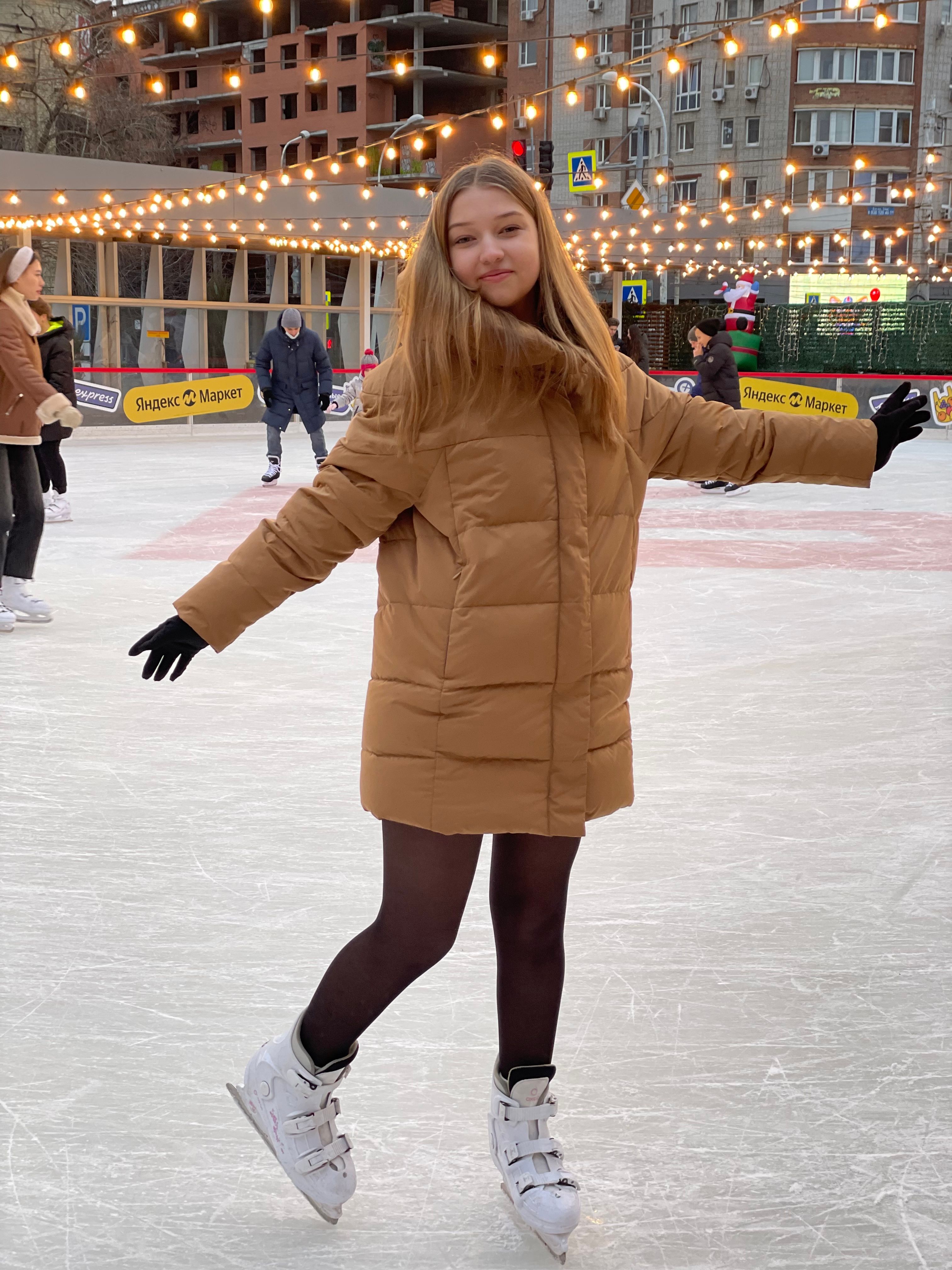 Woman enjoying ice skating on an outdoor rink with festive lights.