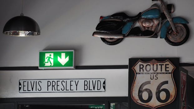 A retro interior decor featuring Elvis Presley Blvd sign, Route 66 sign, and a vintage motorcycle on a wall.