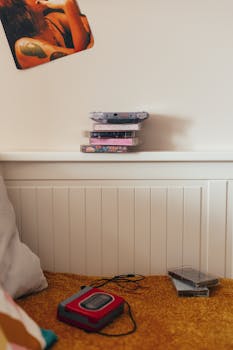 Retro 90s bedroom featuring a stack of cassette tapes, a cassette player, and nostalgic posters.