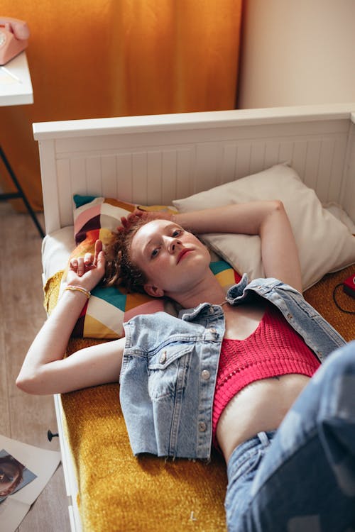 Free Woman in Blue Denim Button Up Vest Lying on Bed Stock Photo