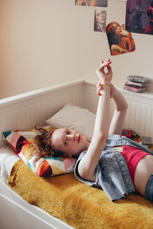 Free Young Woman in Blue Denim Jacket Lying on Bed Stock Photo