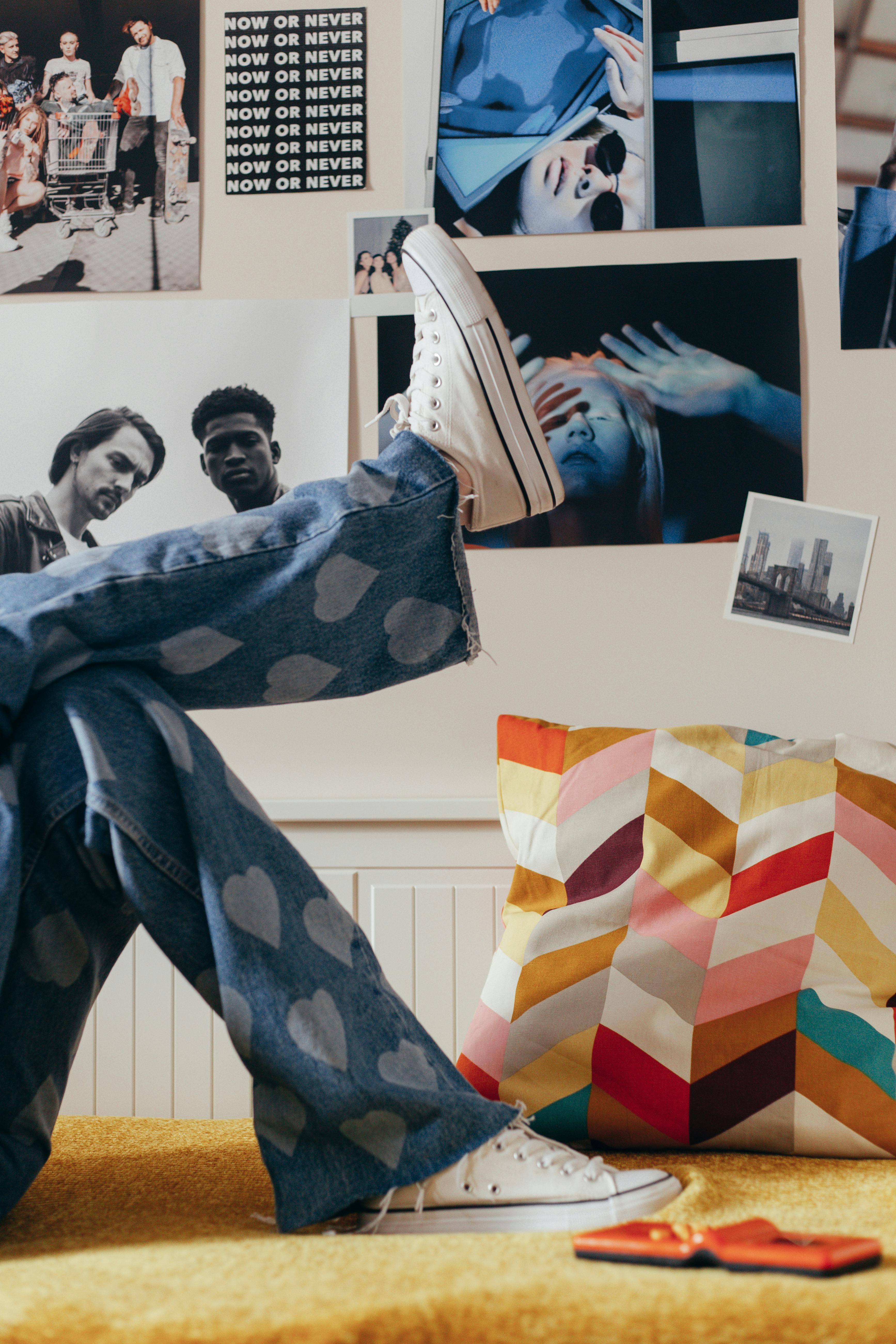 person in blue denim jeans and white sneakers lying on bed