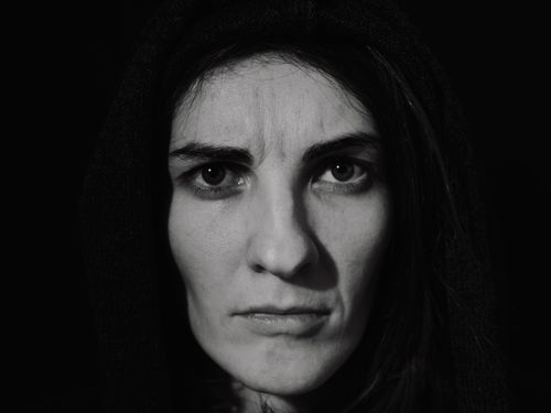Free Close-up black-and-white portrait of a woman with a serious expression, wearing a hood. Stock Photo