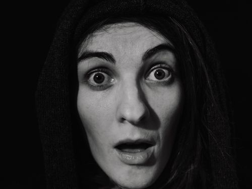 Free A dramatic black and white close-up portrait of a surprised woman with a hood. Stock Photo