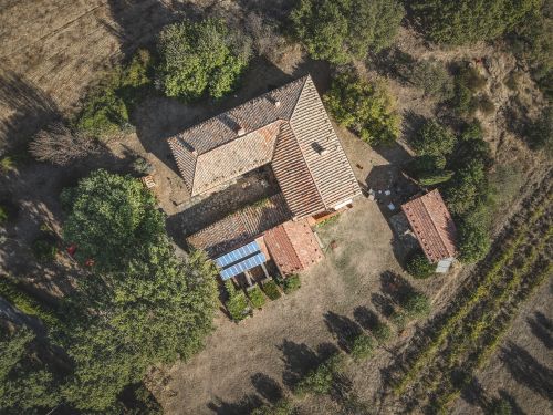 Free Aerial shot of a rustic farmhouse surrounded by greenery in a rural setting. Stock Photo