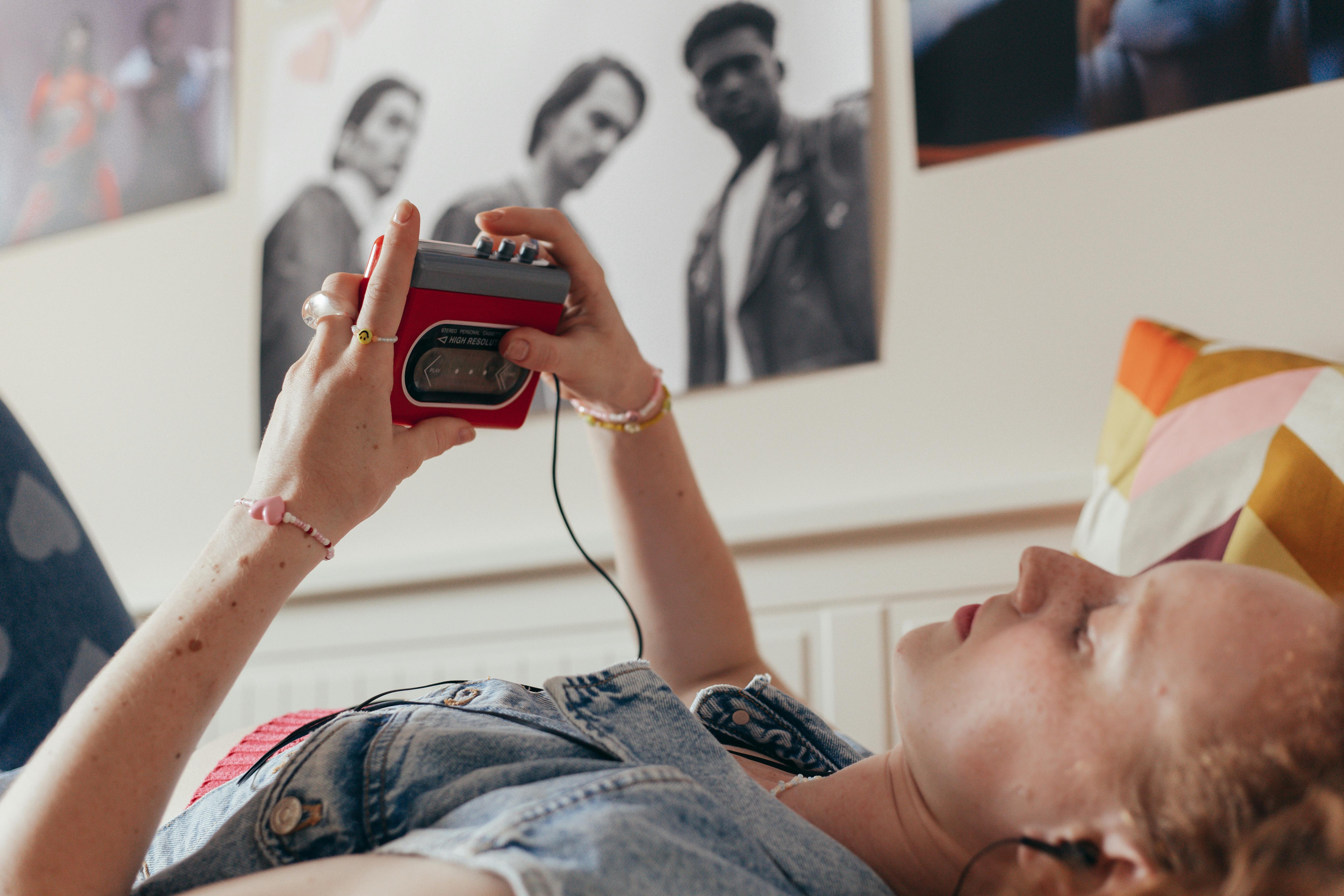 A Woman in a Denim Shirt Listening to Music while Lying Down