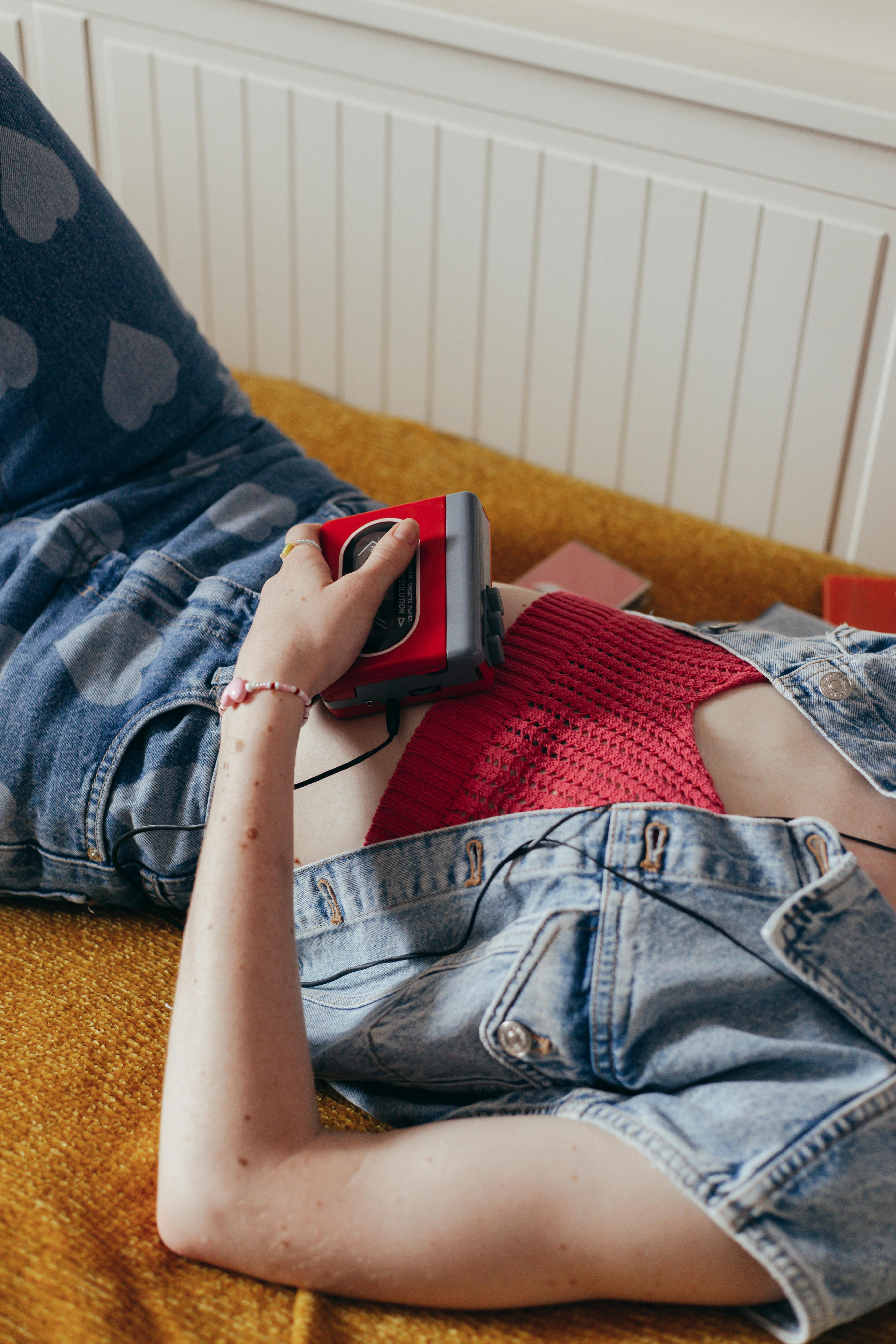 a woman in a denim shirt listening to music while lying down