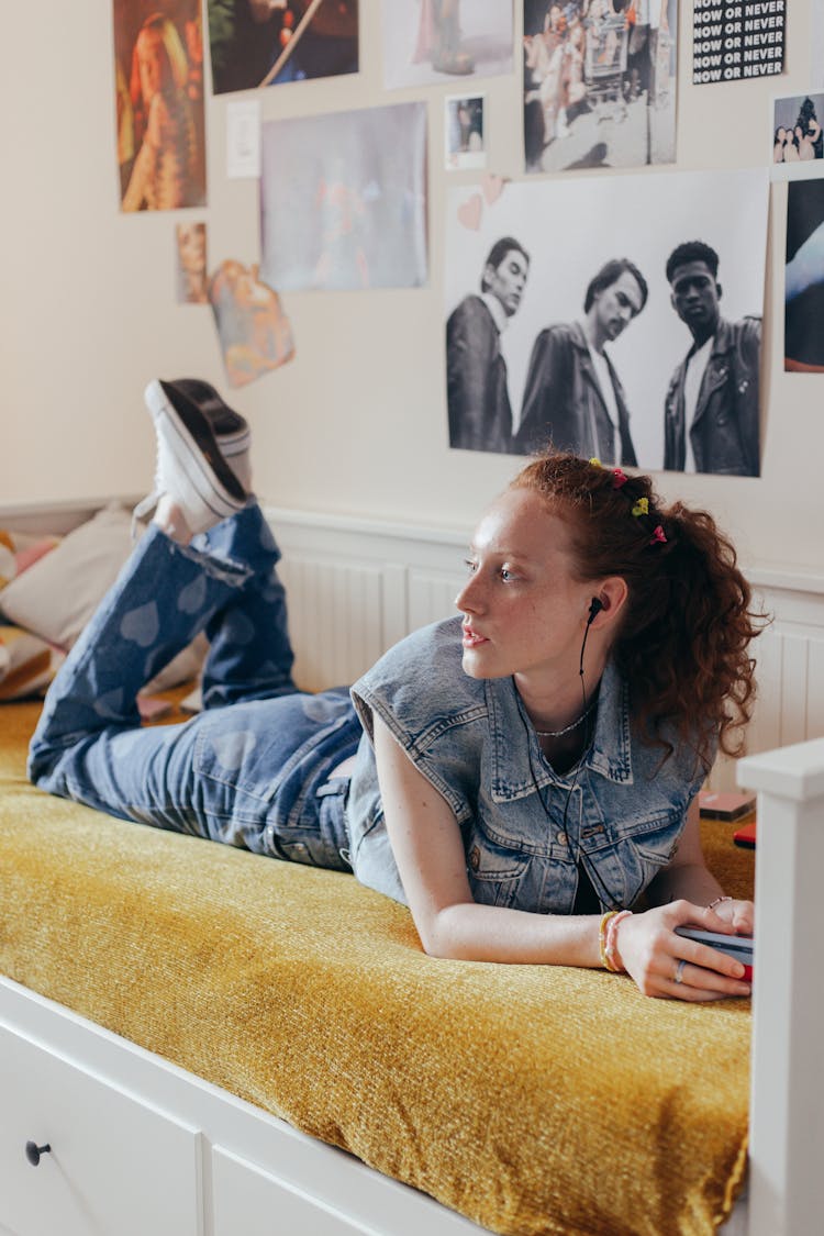 Woman In Denim Vest Lying Down On Bed While Listening To Music