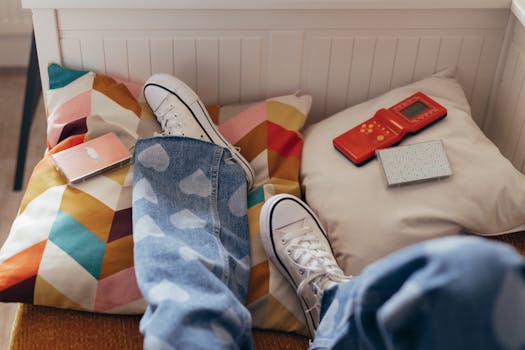 Teenager relaxes indoors with vintage games, colorful pillows, and casual jeans.
