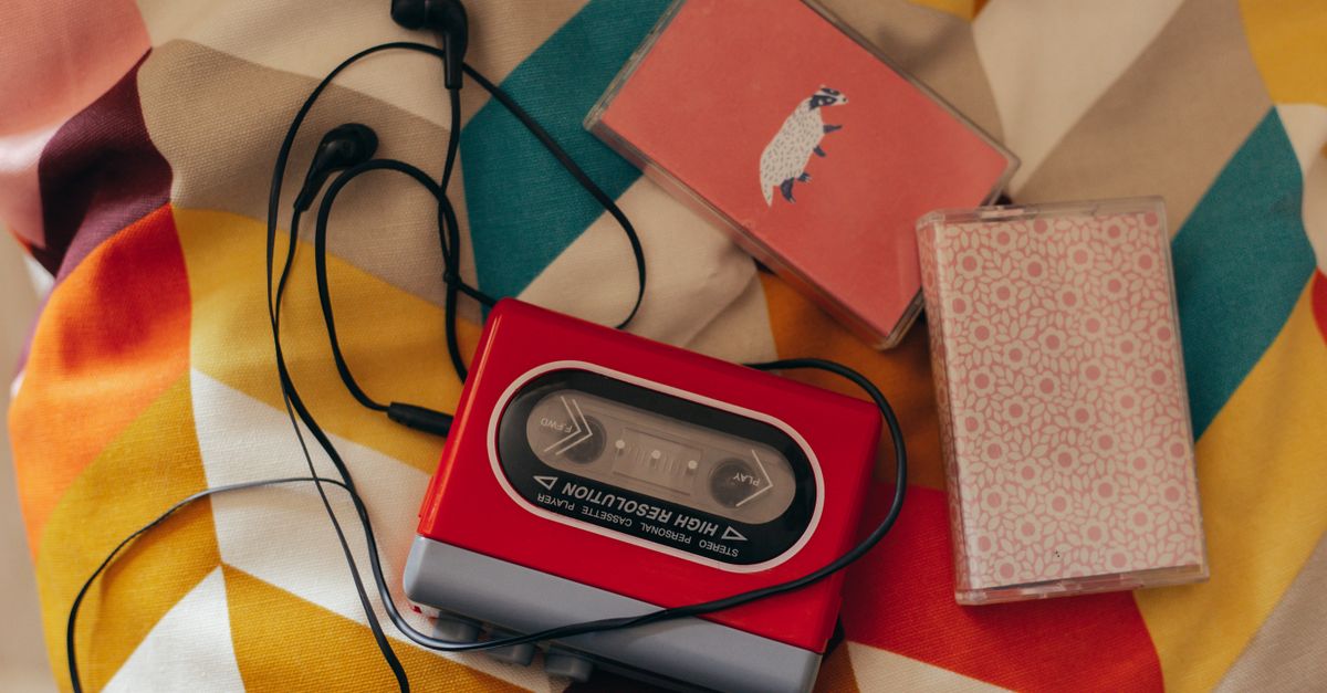 Vintage 90s cassette tapes and a portable CD player next to a smartphone playing Spotify
