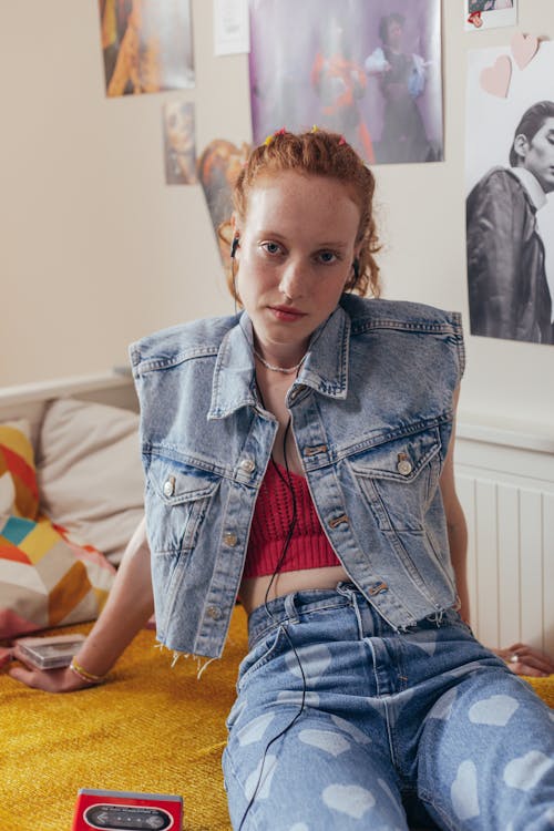 
A Woman in a Denim Vest Listening to Music