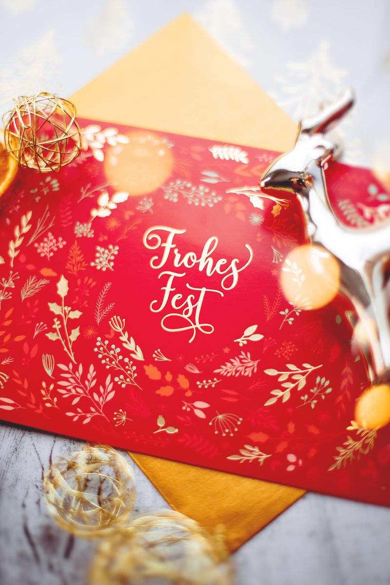 A vibrant red Christmas card decorated with delicate golden patterns and a festive message.