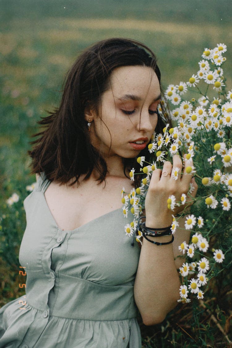 Girl Sitting On The Meadow And Smelling Chamomile Flowers