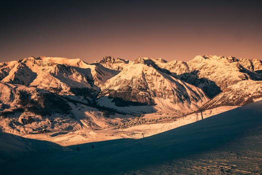 Breathtaking view of snowcapped mountains in Livigno, Italy, under a vibrant sunset sky.