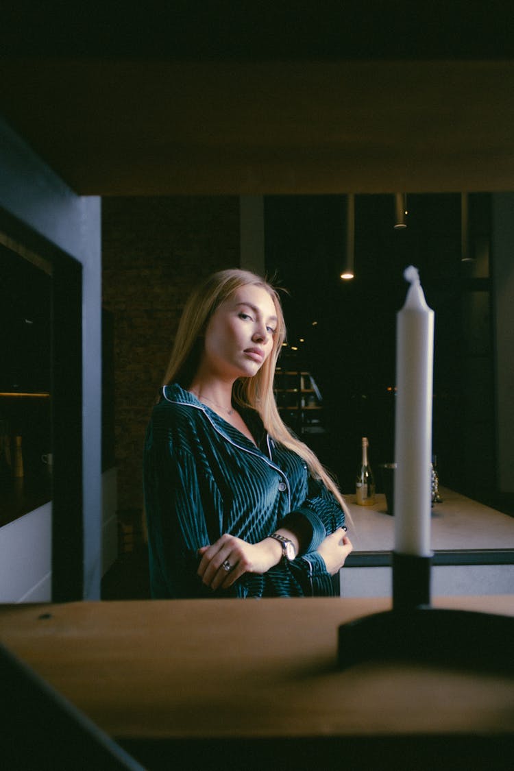 Young Blond Woman Posing From Behind Shelves With White Candle