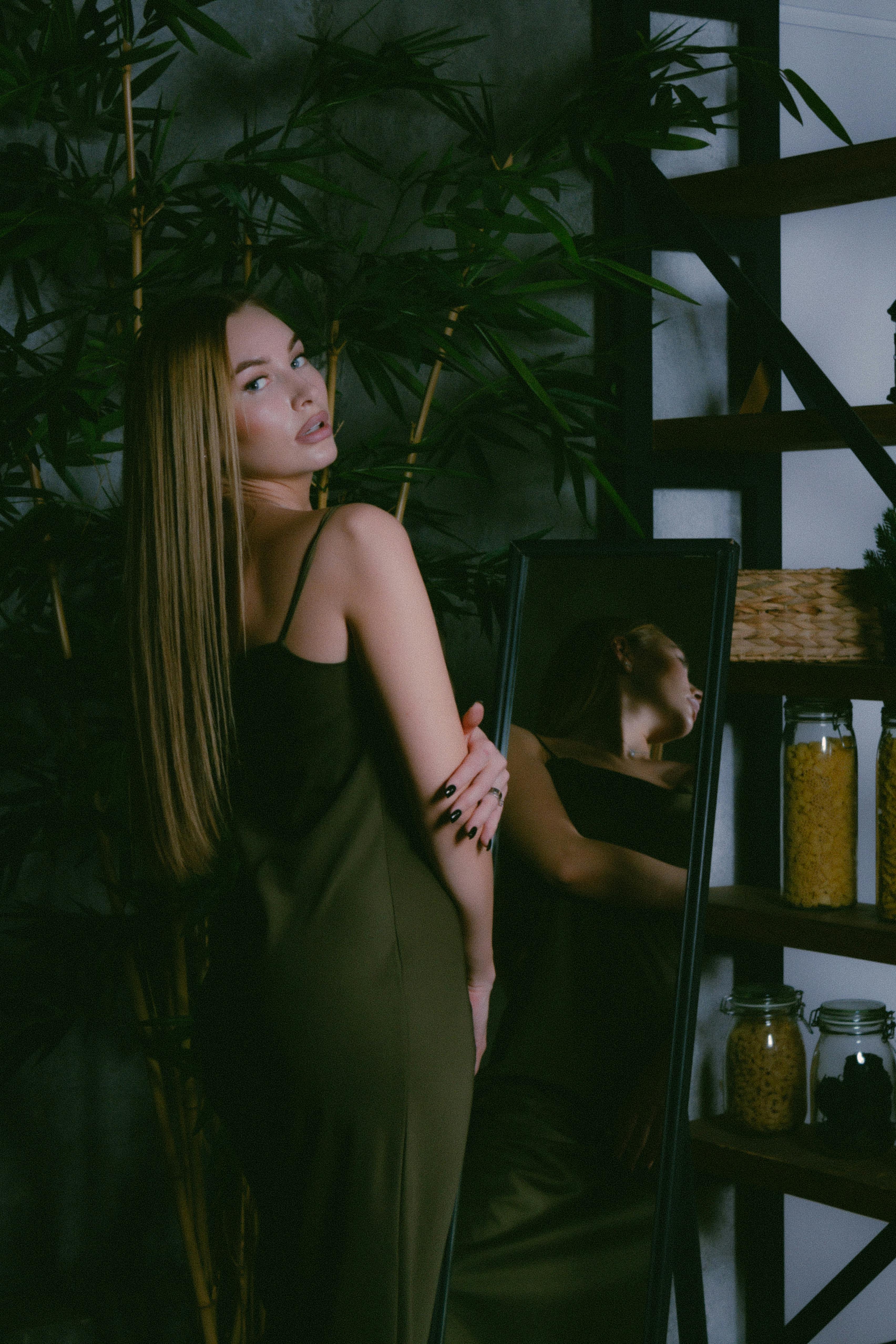 woman with long fair hair standing before mirror and looking over shoulder