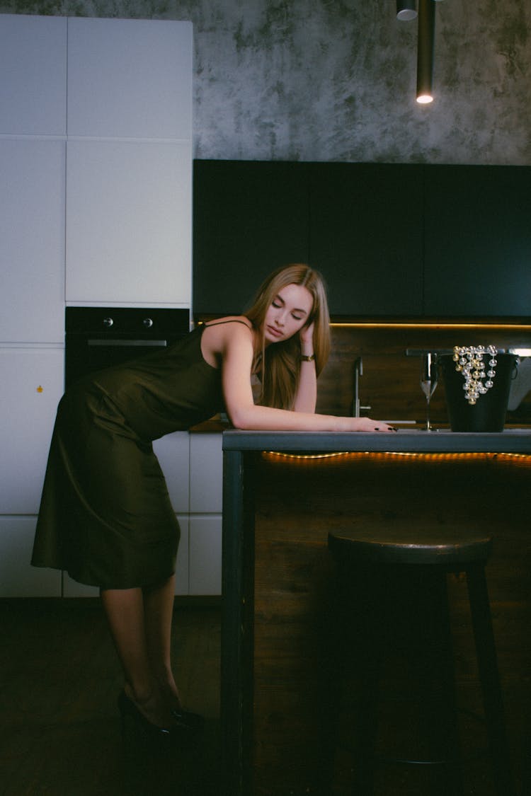 Woman Leaning On The Worktop In The Kitchen